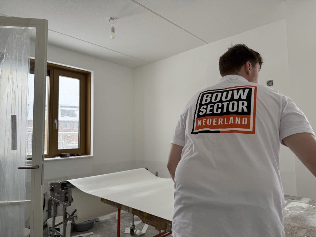 Behanger van Bouwsector Nederland met een baan vlies op de plaktafel in een lege kamer